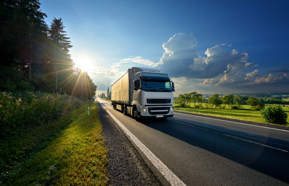 Logistiek transport met vrachtwagen op landelijke weg in de natuur, zonsondergang, logistieke oplossingen, wegennet, vrachtvervoer, Logitrex.nl.