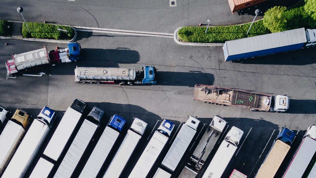Dronetopzicht van vrachtwagens in een logistiek distributiecentrum, logistieke planning en transport, tracering en supply chain management, Logitrex logistieke diensten, efficiënte opslag en distributie.