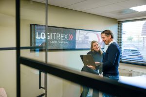 Efficiënt logistiek overleg bij Logitrex met zakelijke teamleden, focus op cargo oplossingen, in kantooromgeving met moderne uitstraling.